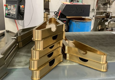 Golden machine parts on a metallic surface, with industrial equipment in the background